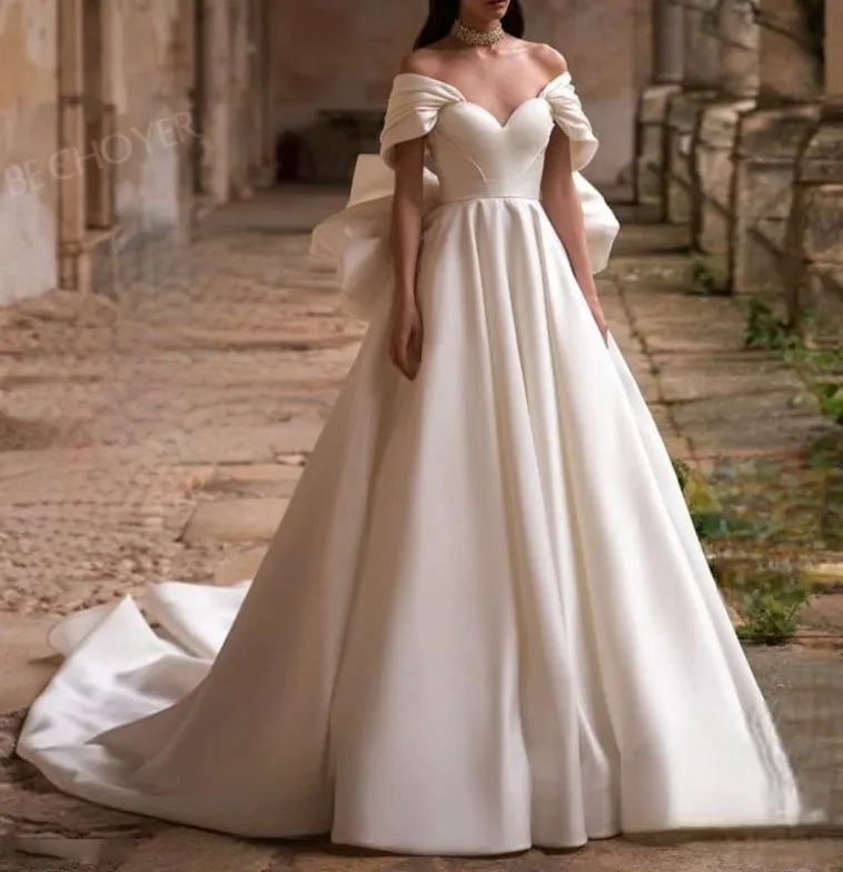 Ellegant off shoulder wedding dress. Satin bow back bridal gown.