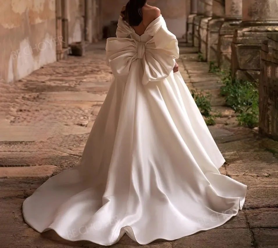 Ellegant off shoulder wedding dress. Satin bow back bridal gown.